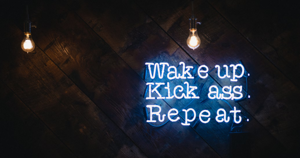 Esta imagem mostra uma frase de néon inspiradora que representa a rotina motivacional de muitos empreendedores: acordar com propósito, agir com confiança e repetir com consistência. Perfeita para ilustrar os componentes da motivação no dia a dia.